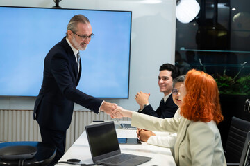 Business professionals shaking hands during a meeting in a modern office, symbolizing partnership, trust, and successful negotiation in a corporate environment.