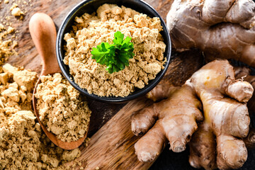 A bowl with ground ginger and its fresh rhizome