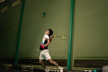 player performing a smash hit during a badminton match on indoor court