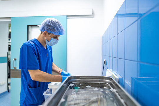 Surgical prep by medical staff. A healthcare worker in scrubs arranges surgical tools at a clean workstation in a bright operating room.
