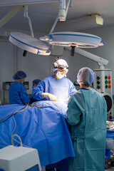 Surgeons operate in sterile space. Surgeons in blue attire work meticulously during a surgical...
