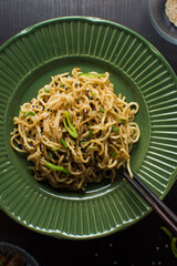 overhead view of scallion noodles on a green plate, top view of onion ramen noodles