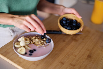 Portrait of a young woman preparing and eating breakfast, drinking juice in the kitchen at home