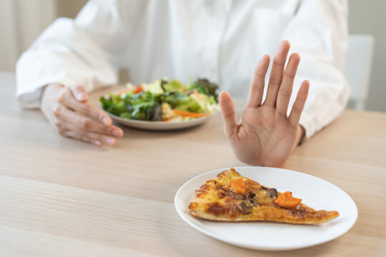 Diet concept, asian young woman close up hand push out away Pizza, refuse junk process, carb food on plate, choose green vegetable salad, eat low fat for good health. Female people getting weight loss
