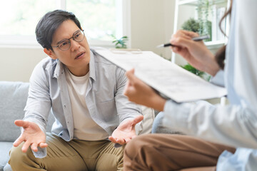 Obraz premium Psychology, depression. Sad, suffering asian young man, male consulting with psychologist, psychiatrist while patient counseling mental with doctor hand taking notes at clinic. Encouraging, therapy.
