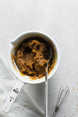 Overhead of peanut butter sauce being mixed in a ceramic cup, process of making creamy savory peanut sauce