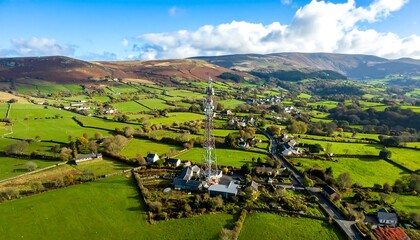 A vibrant rural landscape displays rolling hills, lush green fields, and a communication tower standing tall amidst the countryside.