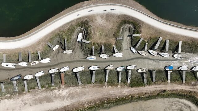vue a&eacute;rienne &agrave; mar&eacute;e basse de l'Ile-de-R&eacute;, avec des bateaux sur des pontons et une piste cyclable avec des touristes &agrave; v&eacute;lo en train de se balader au bord d'un &eacute;tang int&eacute;rieur