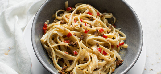 top view of creamy peanut sauce on noodles, overhead view of peanut noodles in a grey bowl