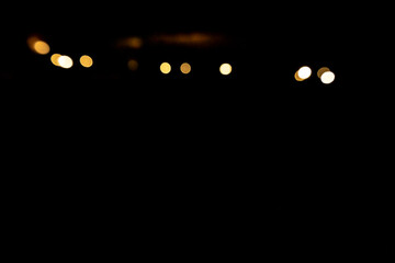 Abstract bokeh lights glowing in darkness, unfocused night scene.