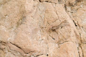 Aged stone with visible signs of natural erosion and texture degradation. Eroded rock with signs of long-term exposure to wind, water, and temperature changes. Surface shows wear and breakdown.