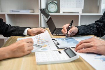 Fototapeta premium Two people are sitting at a desk with papers and a calculator