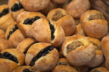 Pile of small round bread rolls filled with sweet or savory ingredients such as black beans and chestnut paste