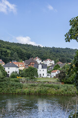 Obraz premium Traditional houses by the river with forested hillside background in Germany