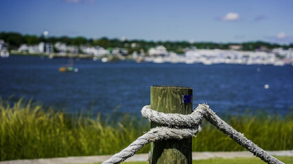 Obraz premium Rope tied to a wooden post with a tranquil waterfront view during a sunny day