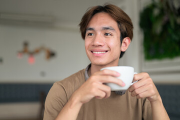Young Thai student man in coffee shop wearing headphones