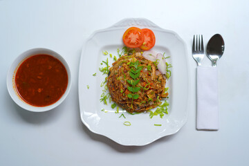 Hot Chicken Kottu with Bowl of Gravy Served on White Plate.