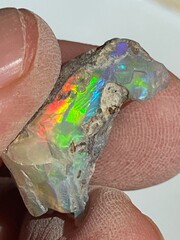 Holding a piece of rainbow colored rough opal