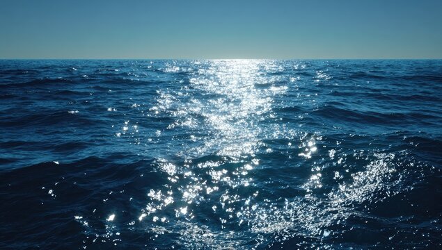 Sunlit expanse of deep blue ocean, gently undulating waves reflecting shimmering sunlight, clear horizon under a vibrant sky