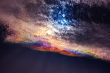 a dramatic sky featuring a vivid rainbow-like gradient stretching horizontally across the image...