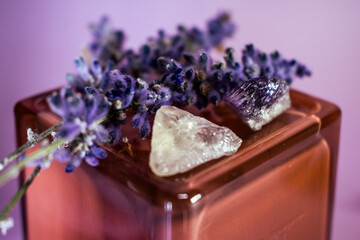 Lavender flowers with rough crystals on amber glass against a soft lavender background, symbolizing tranquility, spiritual growth, and a natural connection to well-being.