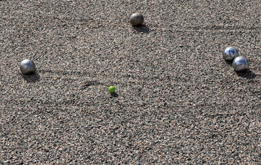 Boule or petanque game. Chrome balls and small jack. Graveled background.