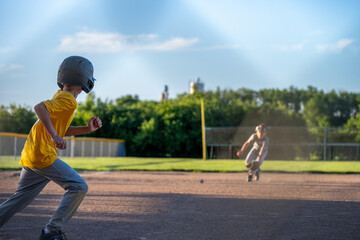 Kids playing baseball at a sunny field during late afternoon with focus on base running and catching