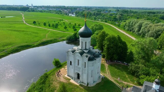Bogolyubova, Russia - May 13, 2024: A view of the famous Church of the Intercession on the Nerl, a historic Russian Orthodox church situated by a river in a serene, green landscape