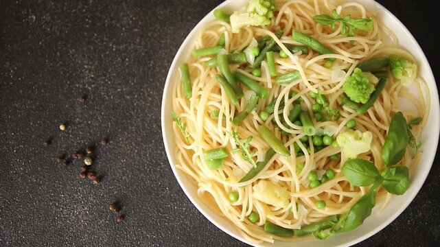 Spaghetti vegetables green peas, broccoli, string beans, kohlrabi vegetarian pasta tasty snack fresh delicious gourmet food background on the table rustic top view copy space vegan food