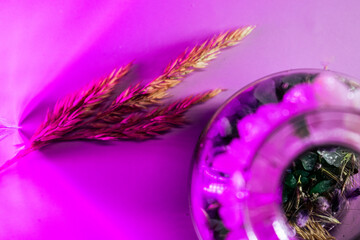 Raw amethyst and clear quartz crystals arranged with dried wheat on a purple surface, evoking...