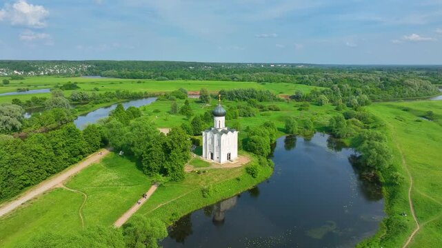 Bogolyubova, Russia - May 13, 2024: A high-angle drone shot of the Church of the Intercession on the Nerl, located at the bend of a river surrounded by lush green meadows