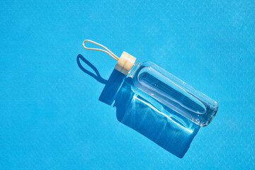 Reusable glass water bottle on blue mat