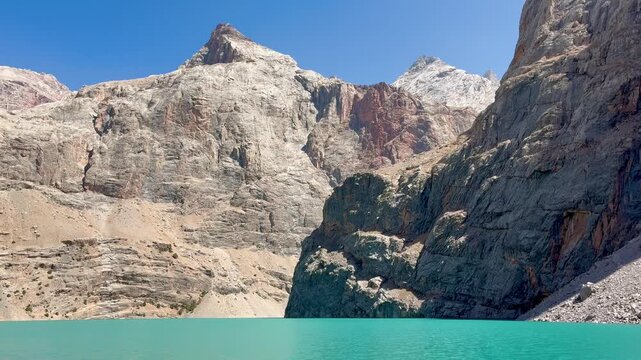Big Allo lake view with mountain range and turquoise water and a small hiker's silhouette in Fann mountains Pamir Alay Tajikistan