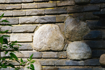 Rustic stone wall with large natural rocks embedded in layered brick construction