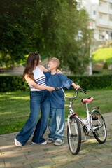 Obraz premium Mother and son standing next to bicycle together in green park on a sunny day