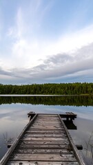 Calm lake with wooden dock at dawn