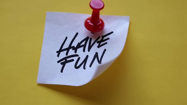 white sticky note with the words Have Fun written on it, attached with red push pin to yellow background