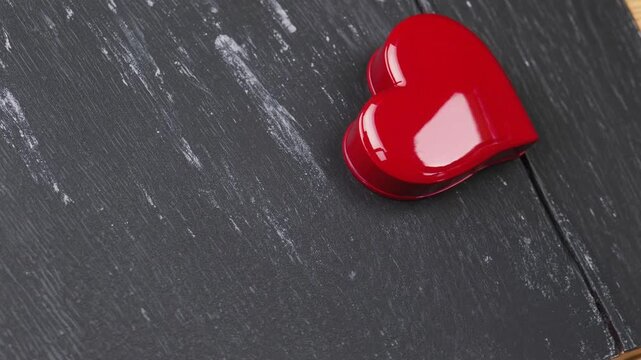 red heart-shaped box filled with candies, presented on rustic black chalkboard background