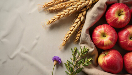 Fresh apples in basket with wheat and flowers on fabric background
