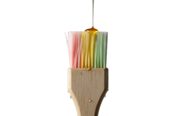 A colorful pastry brush with a drop of golden honey or syrup dripping from its bristles onto a dark background isolated on transparent background