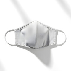 A white fabric face mask with ear loops is shown against a white background with soft shadows.