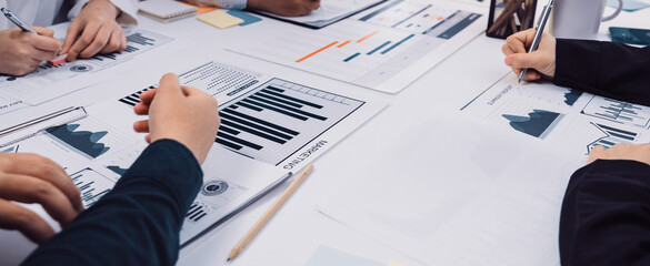 A collaborative office setting featuring hands engaged in analyzing charts and graphs. The image captures a business meeting dedicated to strategy and growth planning. SACTR