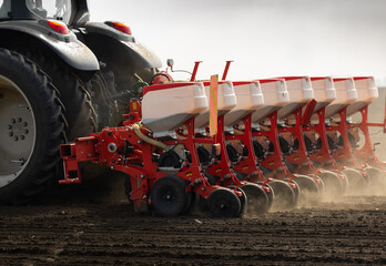 Farmer with tractor seeding in sunset