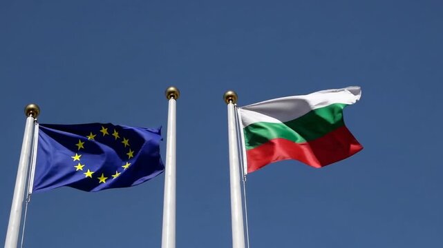 Flags of the European Union and Bulgaria are waving on the flagpoles against clear blue sky