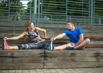 Smiling and joyful couple doing fitness exercises, in city park