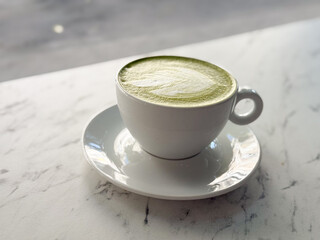 Matcha latte in white ceramic cup on saucer. Japanese tea culture, healthy lifestyle and modern cafe trend.