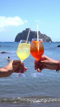 cheers with cocktails on a mediterranean beach with castle view