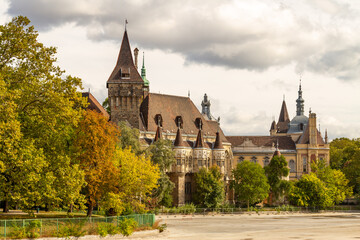 Fototapeta premium Vajdahunyad Castle in City Park showcasing eclectic architecture with Romanesque, Gothic, Renaissance, and Baroque styles, surrounded by golden autumn foliage. Budapest, Hungary.