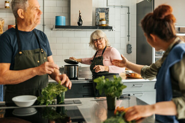 Female chef assisting senior woman preparing food during cooking class in commercial kitchen