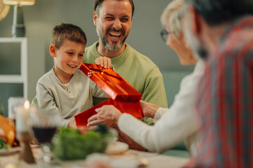 Happy family opening christmas gift at home during lunch or dinner